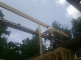 Carpenter setting a ridge beam over a new addition frame — Ice Dam Removal by Roofing Brothers in Newdale