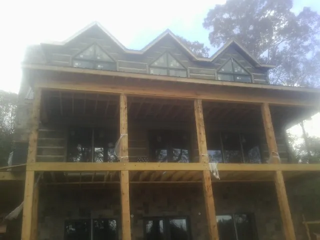 Dormers and porch framing on a large log home under construction — Roof Coating work by our crew in Newdale