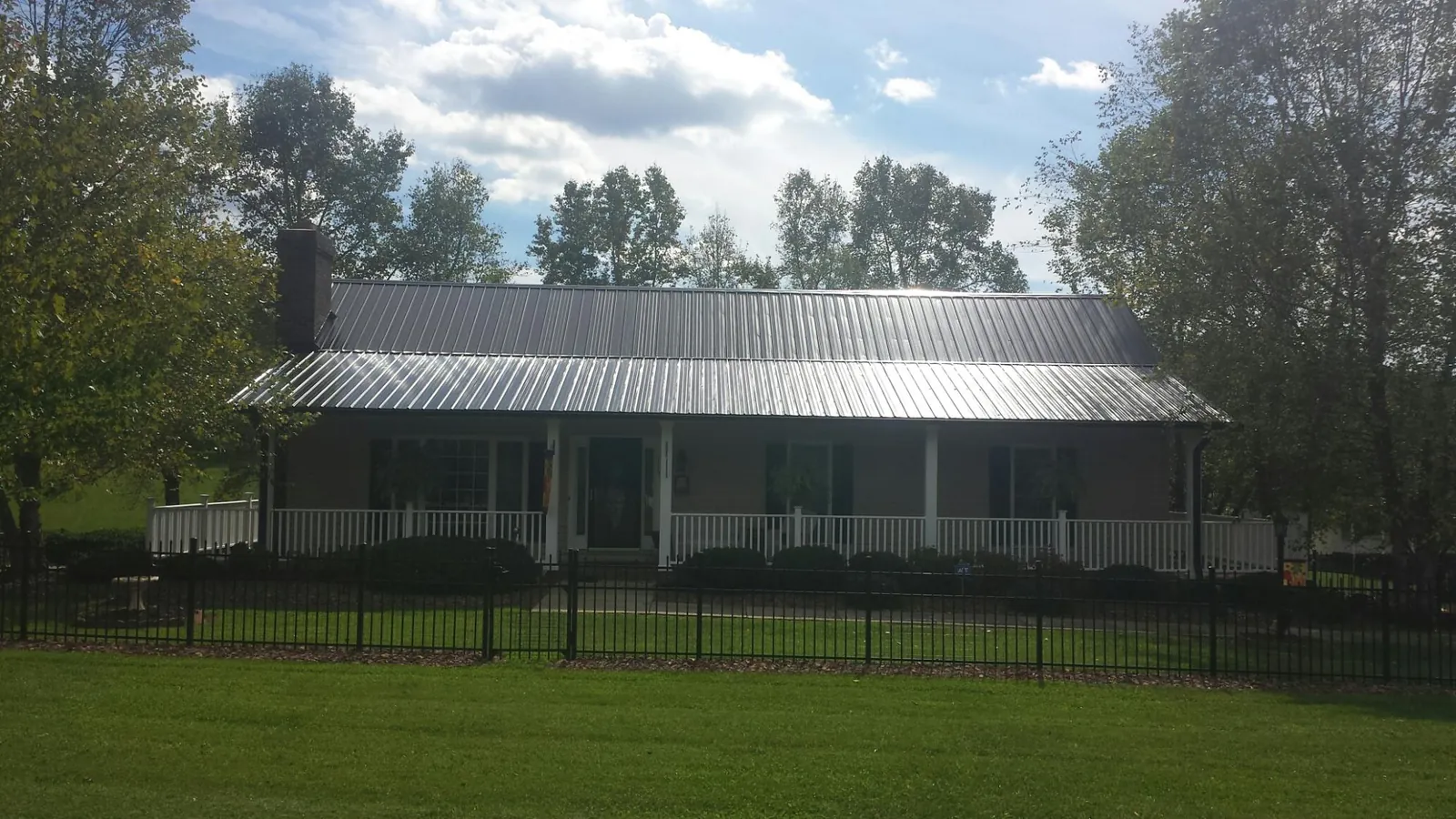 Gray metal roof on a brick ranch with a full width front porch — Gutter Guard Installation work by our crew in Newdale