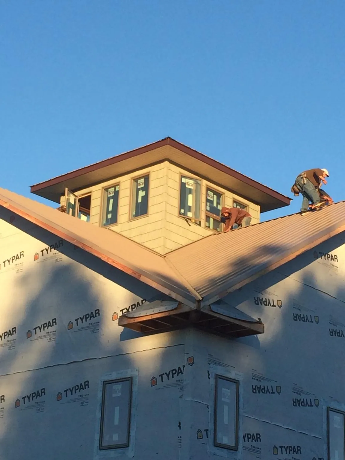 Roofers working around a rooftop cupola on a new metal roof at sunset — Roof Waterproofing in Newdale by Roofing Brothers